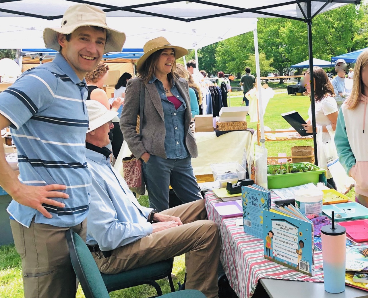 Three people behind a table that has seeds and dirt on it. A child stands on the other side of the table, just out of view.