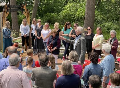 Crowd gathered outdoors with large scissor to cut ribbon at event