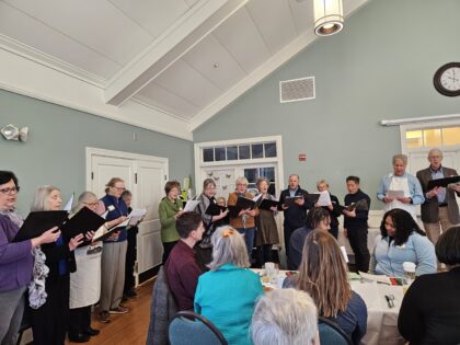 First Parish Choir and friends sing during the celebration accompanied on piano by Music Director, Mary Beth Courtright.